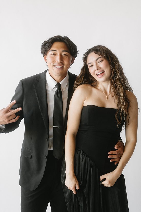 A man in a suit and a woman in a black dress posing together