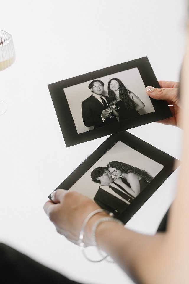 Someone holding two black-bordered photo prints of a couple posing