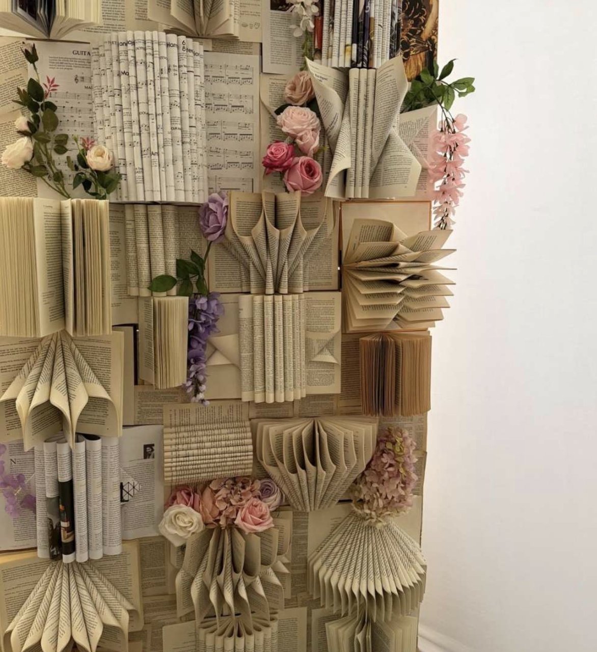 The Book Wall: pages folded into fans, with pink and lavender blooms between them