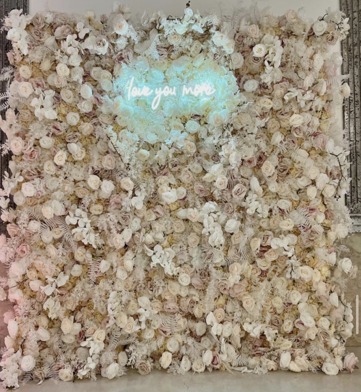 The Sandy flower wall: cream and ivory blooms, with a neon sign